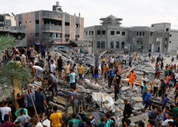 Palestinians walk among the rubble of a building destroyed in Israeli strikes, in the southern Gaza Strip October 9, 2023. REUTERS/Ibraheem Abu Mustafa