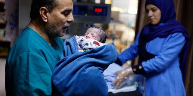 A Palestinian medical worker holds one of the newborn twins of Abu Odah family as midwife Samah Qeshta looks on, at Nasser hospital, amid the ongoing conflict between Israel and the Palestinian group Hamas, in Khan Younis in the southern Gaza Strip, November 2, 2023. REUTERS/Mohammed Salem